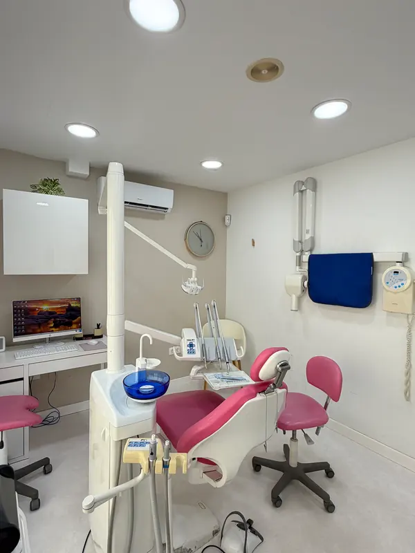 Gabinete dental con sillón rosa y equipo de trabajo